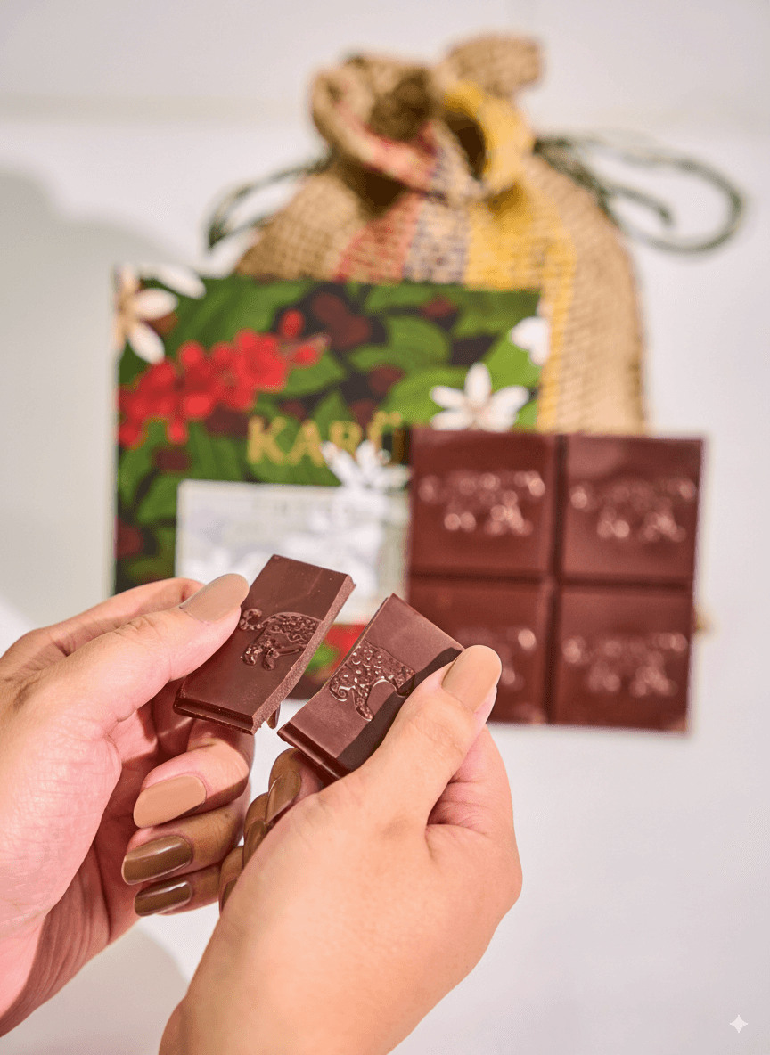 Hands holding 70% chocolate bar with a Karu branded gift bag in the background.