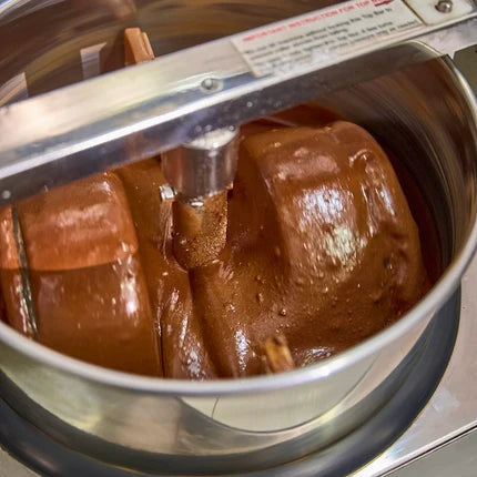 Chocolate mixture being stirred in a large metal bowl with a mixer.
